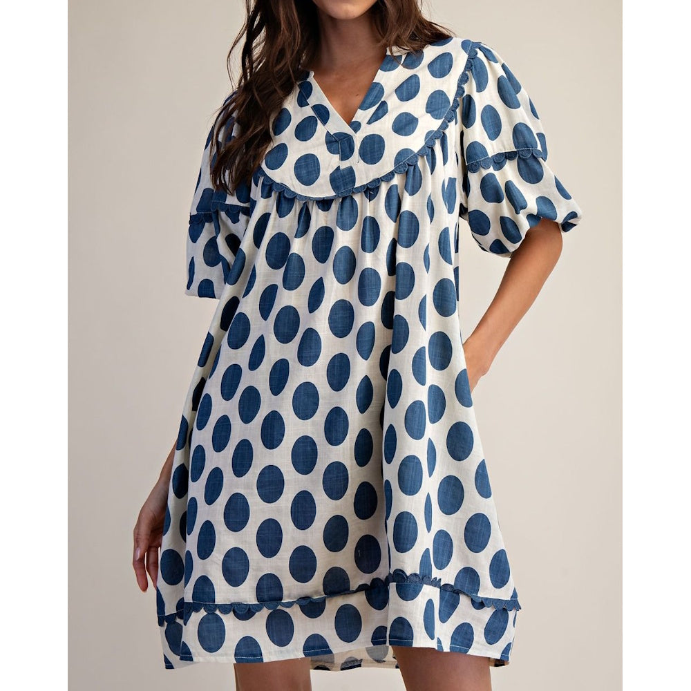 Front view of a blue and white polka dot linen mini dress featuring short sleeves and scalloped trim.