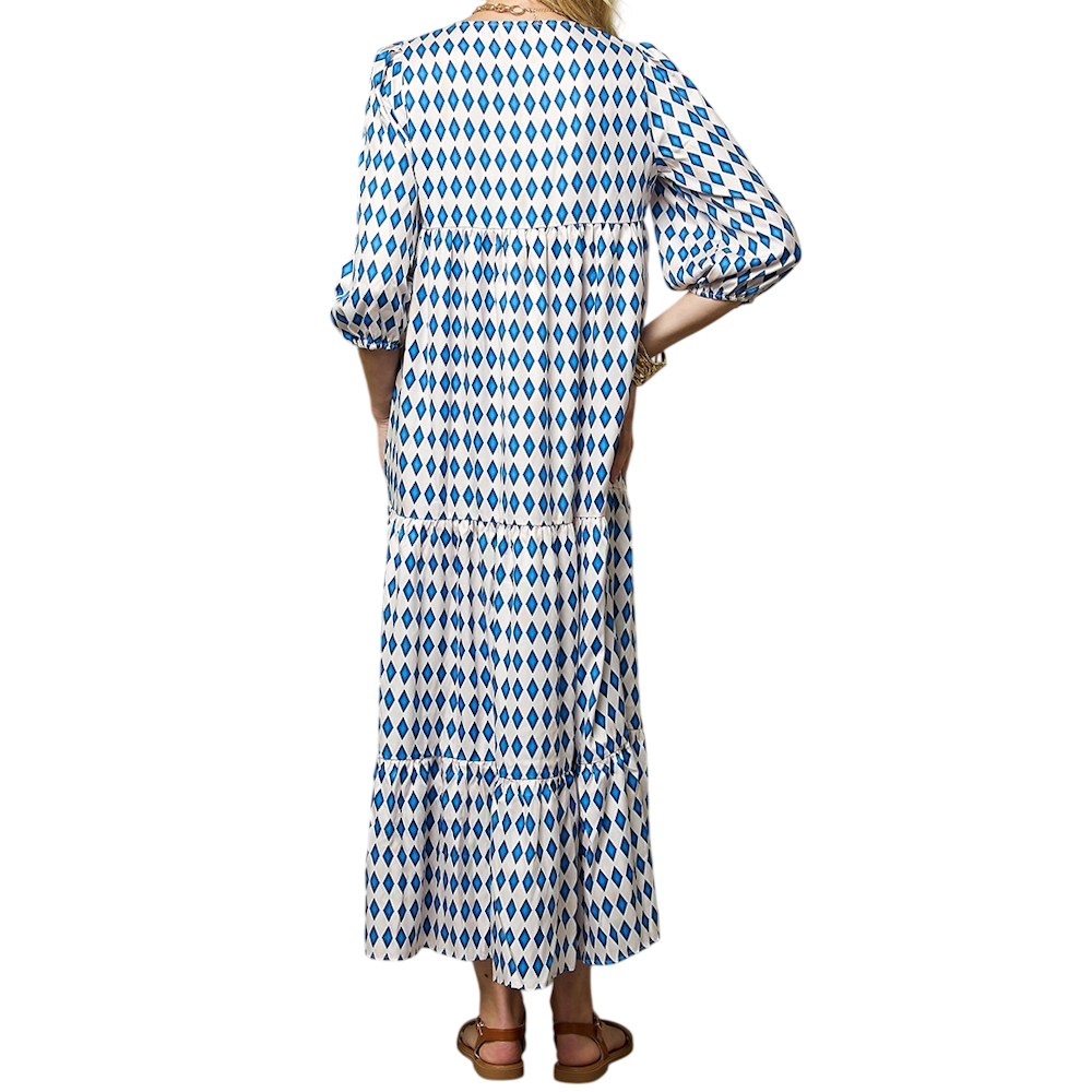 Rear view of a person wearing a tiered, blue and white diamond-patterned maxi dress with three-quarter puff sleeves.