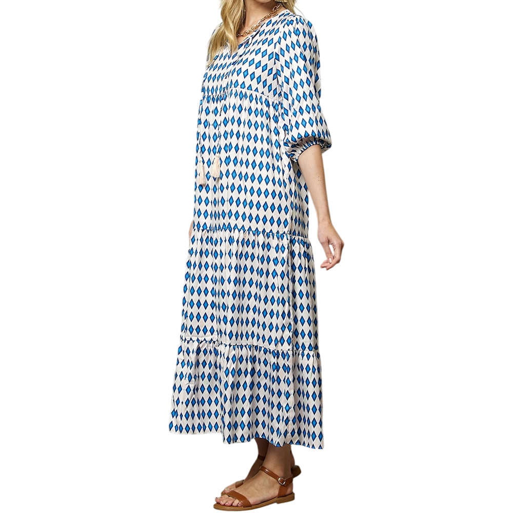Woman in a blue and white diamond-patterned tiered maxi dress with three-quarter puff sleeves and sandals.