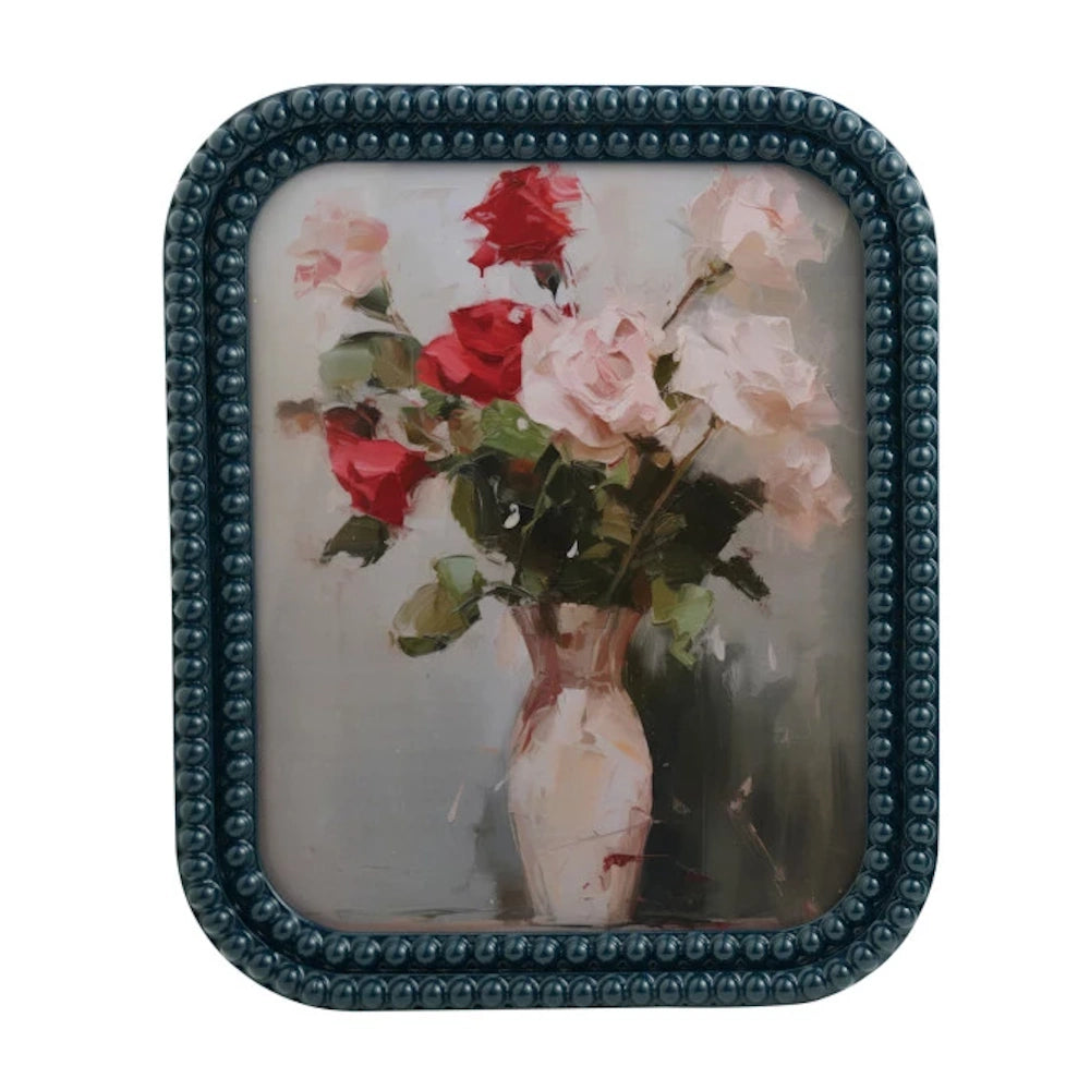 Oil painting of pink and red roses in a vase, set in a teal beaded bobbin frame.