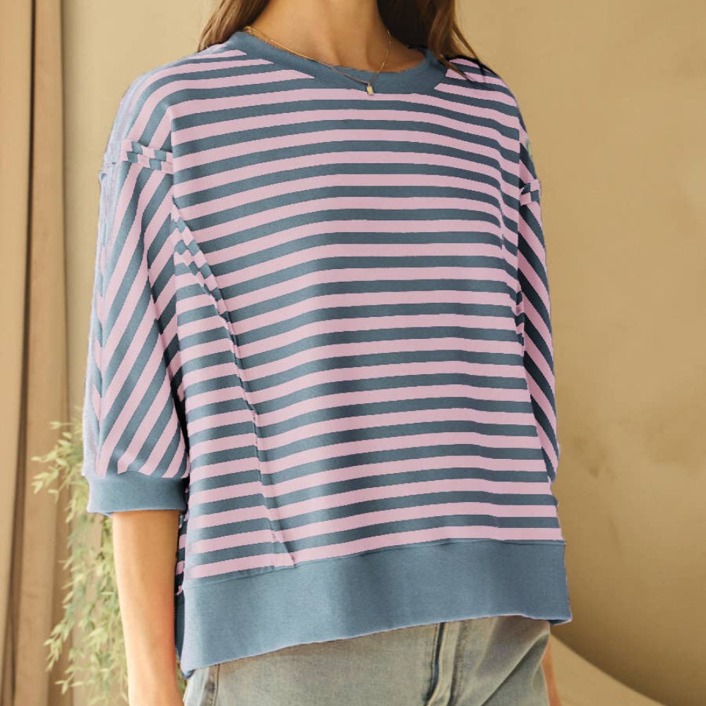 Blue and pink horizontal striped knit top with short sleeves and a wide hem, worn with light-wash denim jeans.