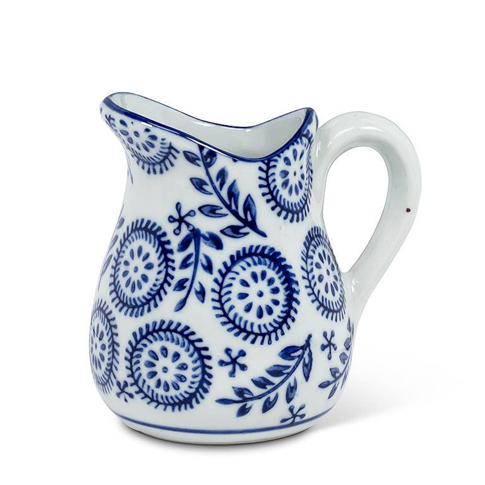 White ceramic pitcher with blue floral and geometric patterns on a white background.