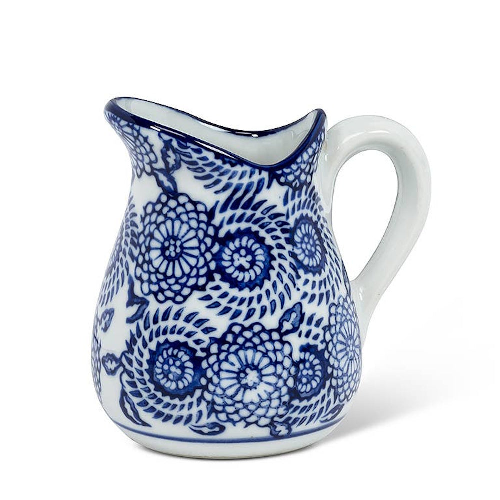 Blue and white ceramic pitcher with intricate floral and swirl patterns and a smooth white handle.