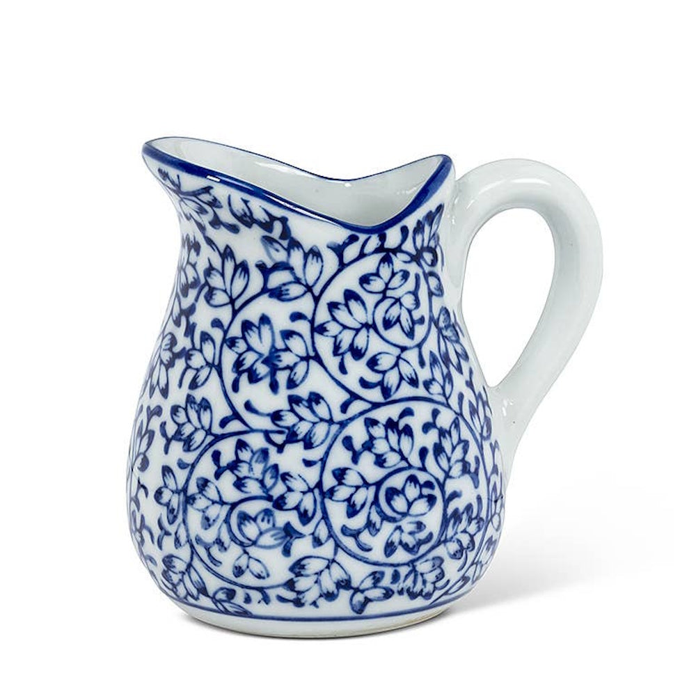 Small blue and white ceramic creamer pitcher with an intricate vine and leaf pattern and a sturdy handle.
