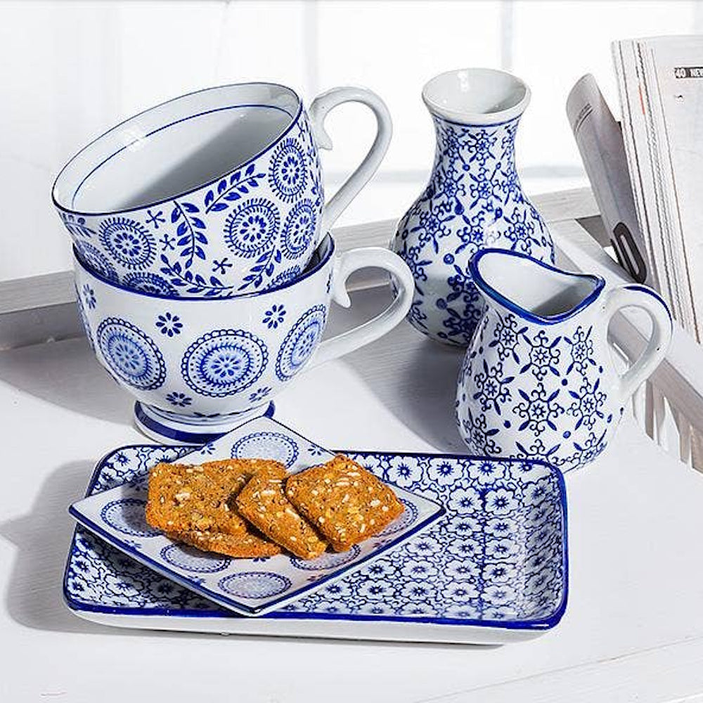 Blue and white ceramic breakfast set with cups, a pitcher, and biscuits on a matching serving tray.