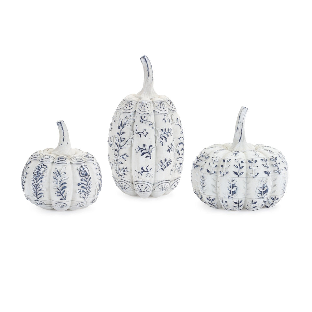 Three decorative white pumpkins featuring blue floral and botanical patterns against a plain background.