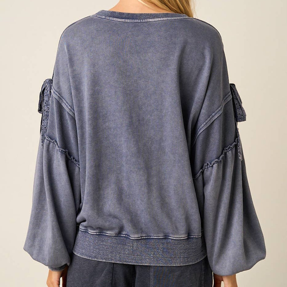 Back view of a blue mineral washed cotton blend sweatshirt with long balloon sleeves and bow details.
