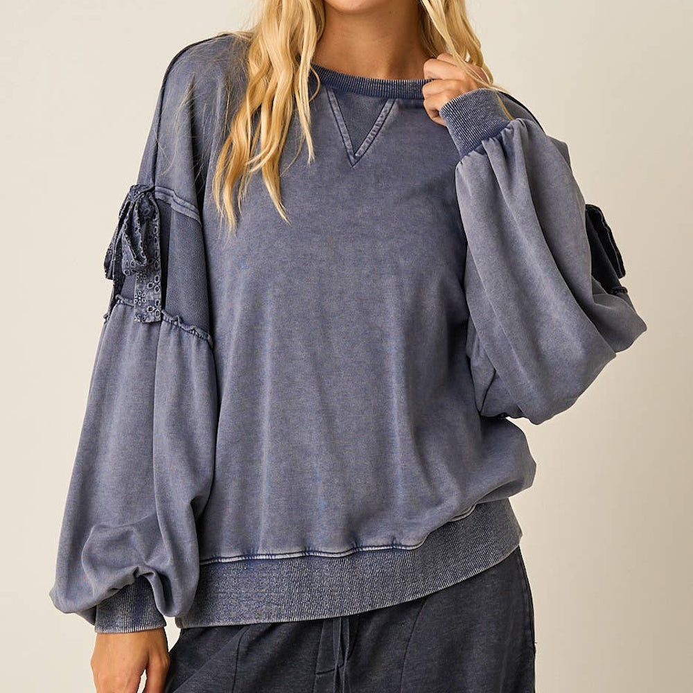 Front view of a blue mineral washed cotton blend sweatshirt with long balloon sleeves and bow details.