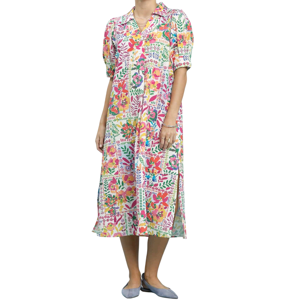 Woman wearing a colorful floral patchwork midi dress with short puff sleeves and a side slit.
