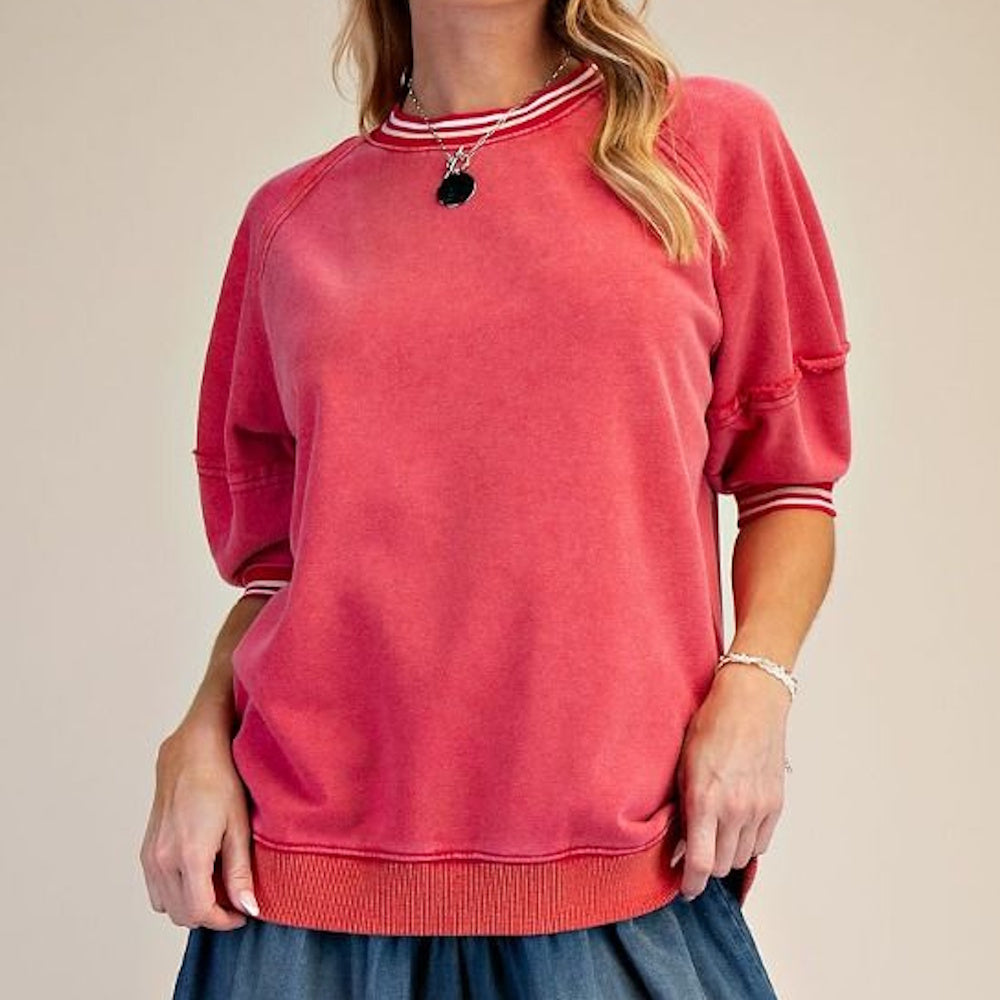 Woman wearing a red short-sleeve sweatshirt with white striped trim on the neckline and cuffs.