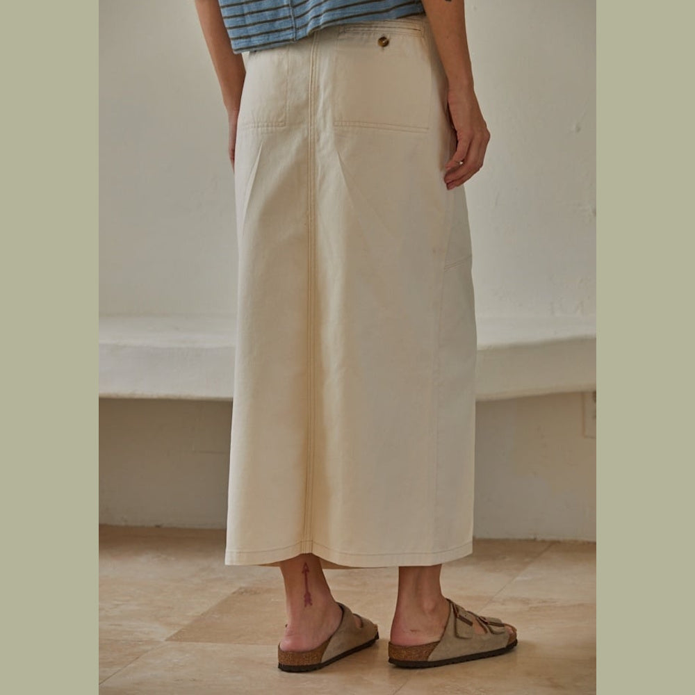 Back view of a person wearing a cream-colored maxi skirt and brown double-strap sandals.
