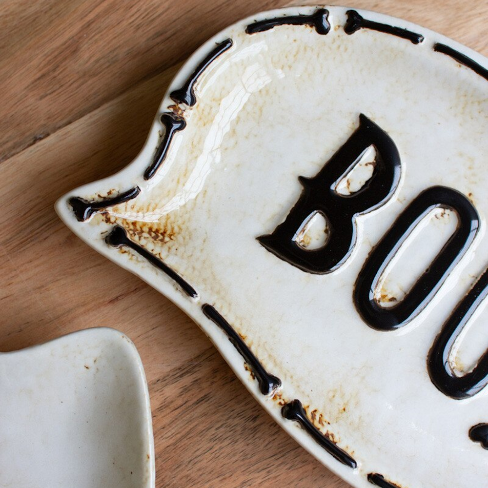 Close-up of a white ceramic Halloween serving platter featuring the word "BOO" with a bone border.