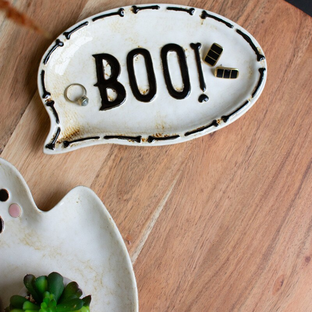 Ceramic speech bubble trinket dish with "BOO!" text on a wooden table.