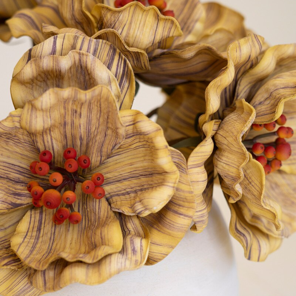 Close-up of yellow-striped artificial flowers featuring detailed ruffled petals and red berry clusters.