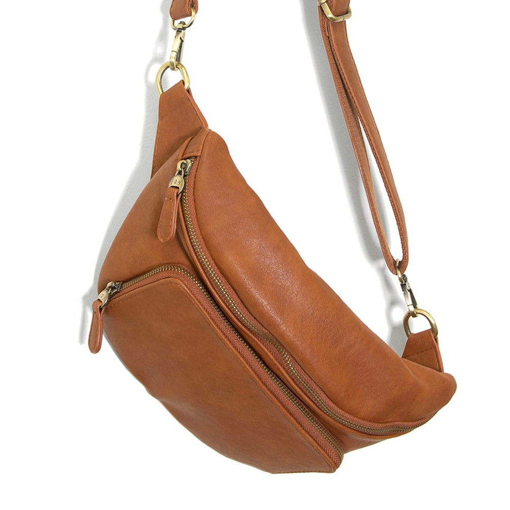 Brown vegan leather sling bag with adjustable shoulder strap and brass zippers, shown on a white background.