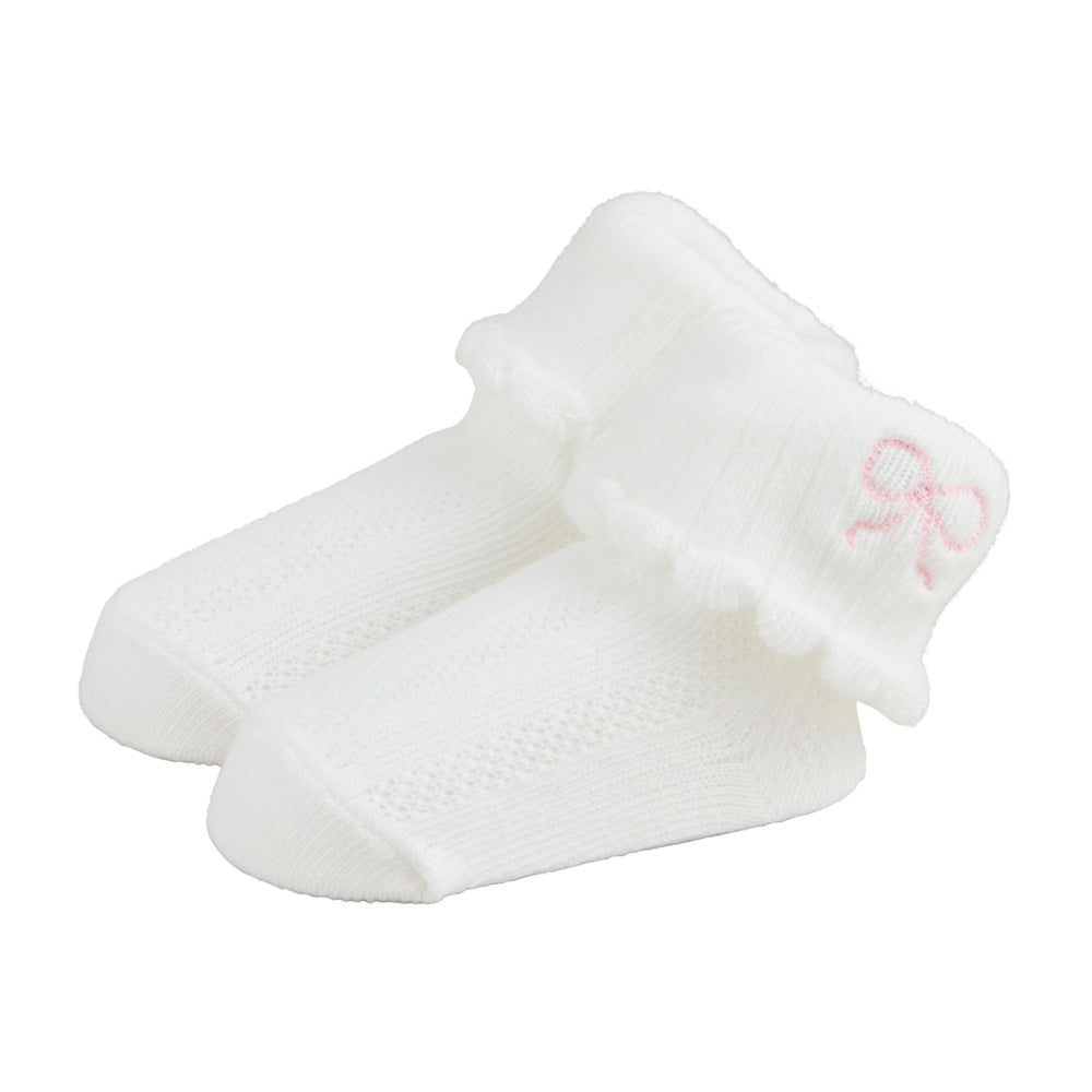 White pointelle knit baby socks in cream with a scalloped foldover cuff and small pink embroidered bow detail.