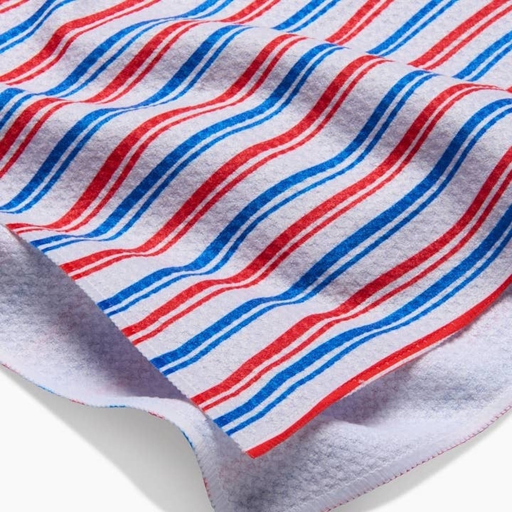 Close-up of a white textured tea towel featuring a pattern of alternating thin red and blue diagonal stripes.