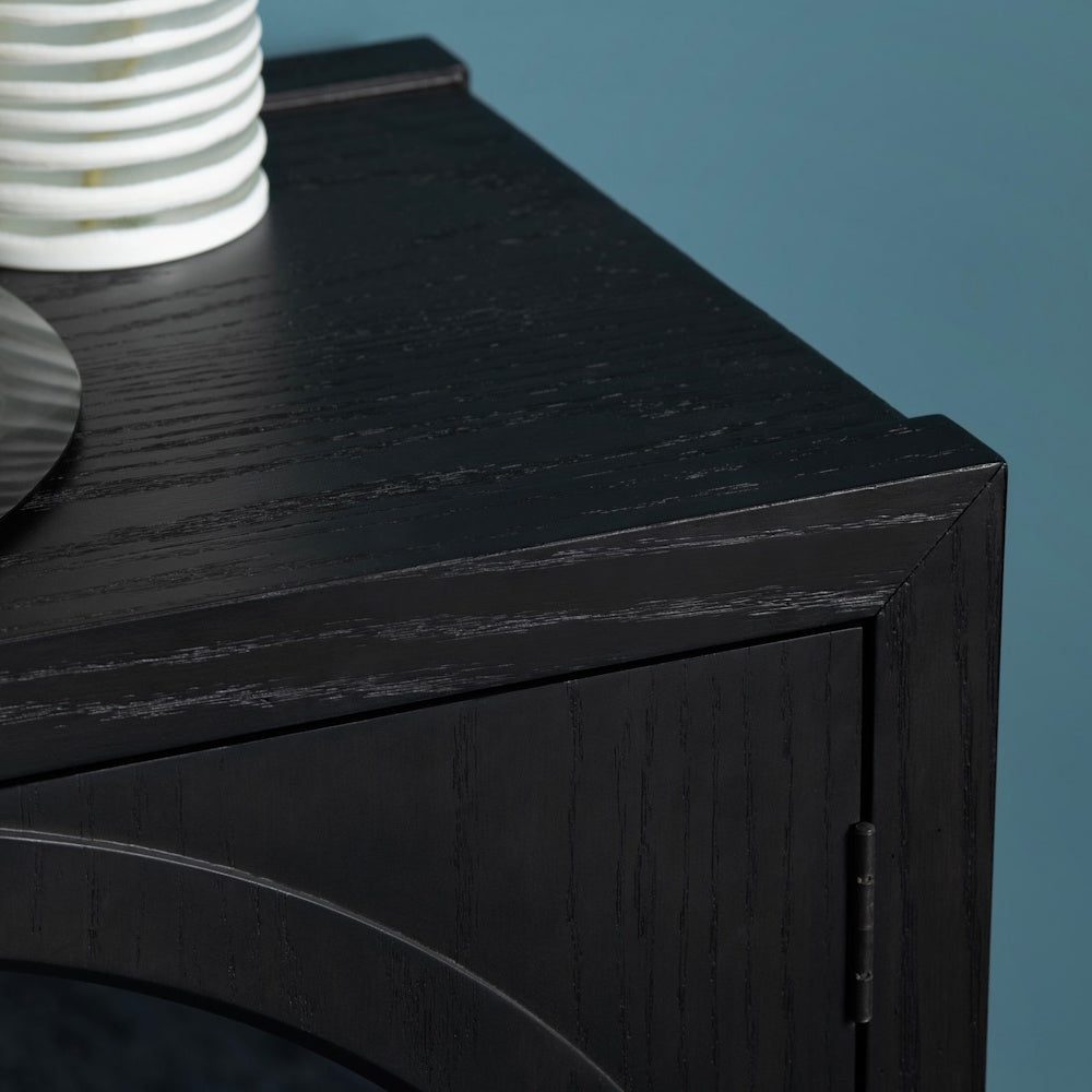 Close-up of a black wood grain sideboard cabinet with an arched design detail and a modern minimalist finish.
