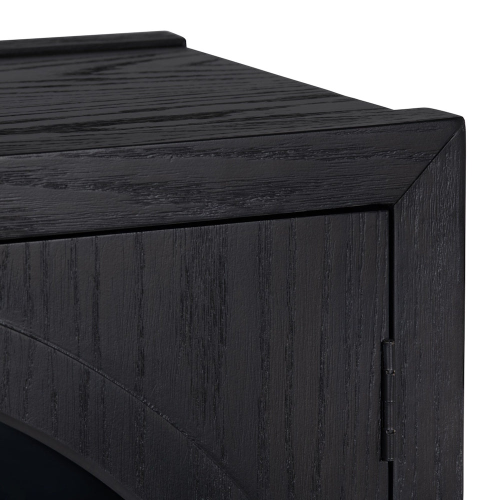 Close-up of black wood grain texture on a modern sideboard cabinet with arched door detail and metal hinge.