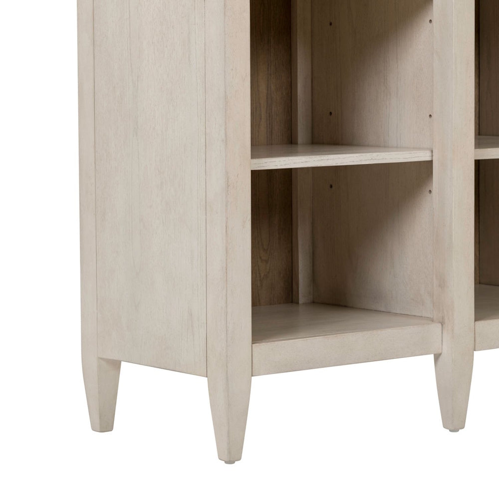 White wood breakfront accent cabinet base with open shelves and tapered legs.