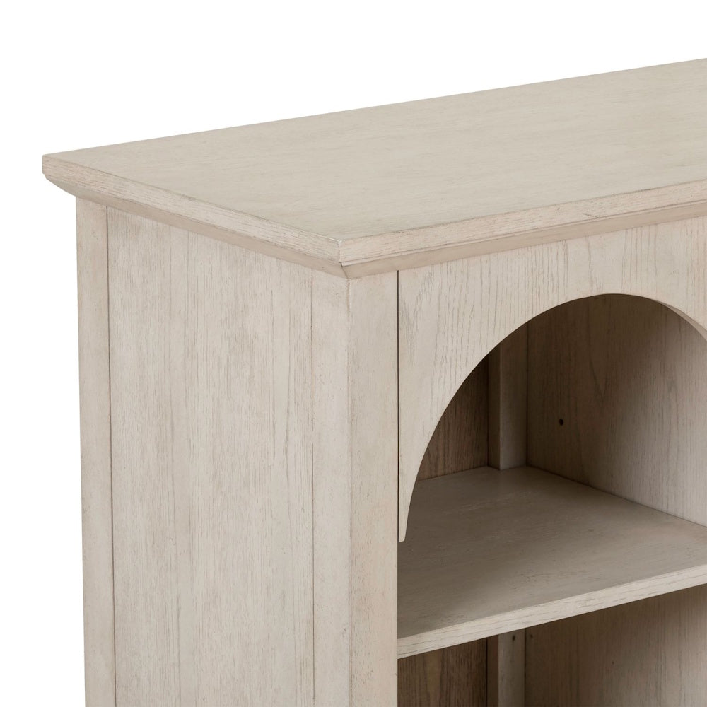 Corner detail of a light wood breakfront accent cabinet showing an arched open shelf.