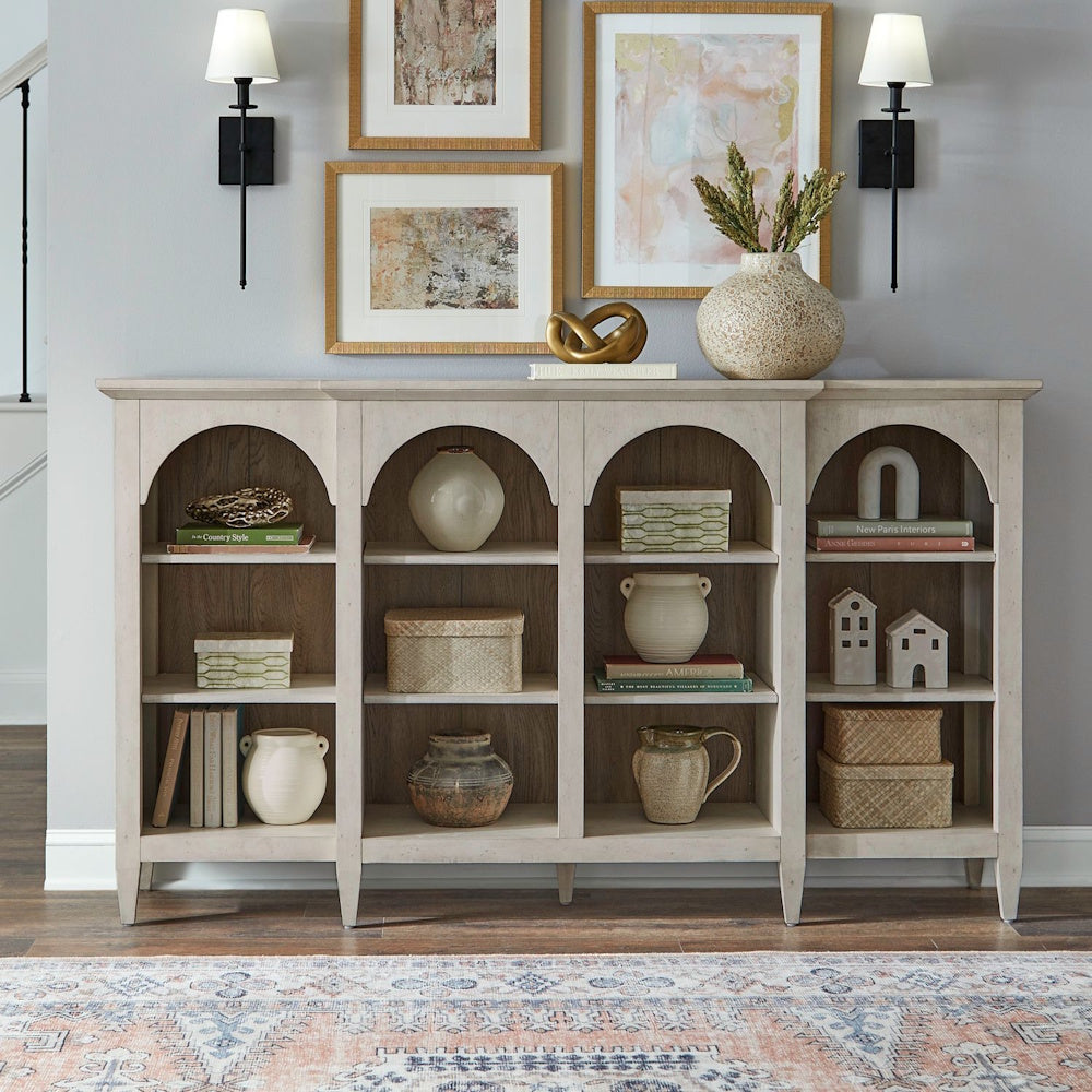 White breakfront accent cabinet with arched open shelves styled with home decor in a living room.