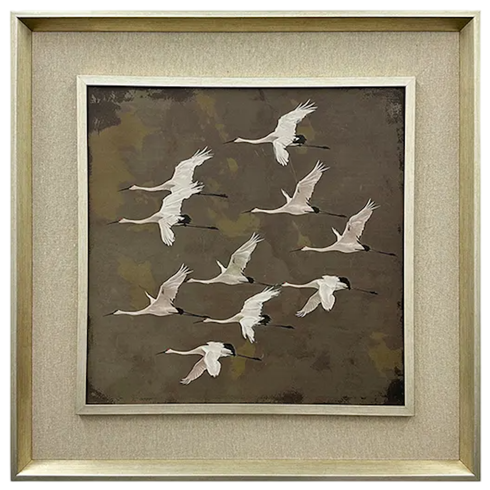 Framed artwork of white cranes in flight against a dark brown, textured background with a metallic frame.