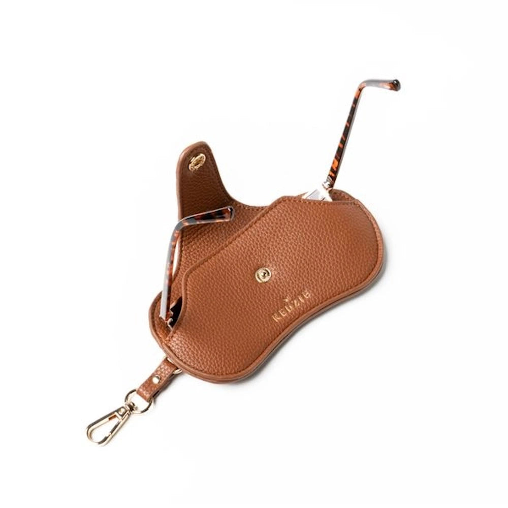 Open brown pebbled leather Kedzie eyewear case with gold snap, showing tortoiseshell glasses inside.