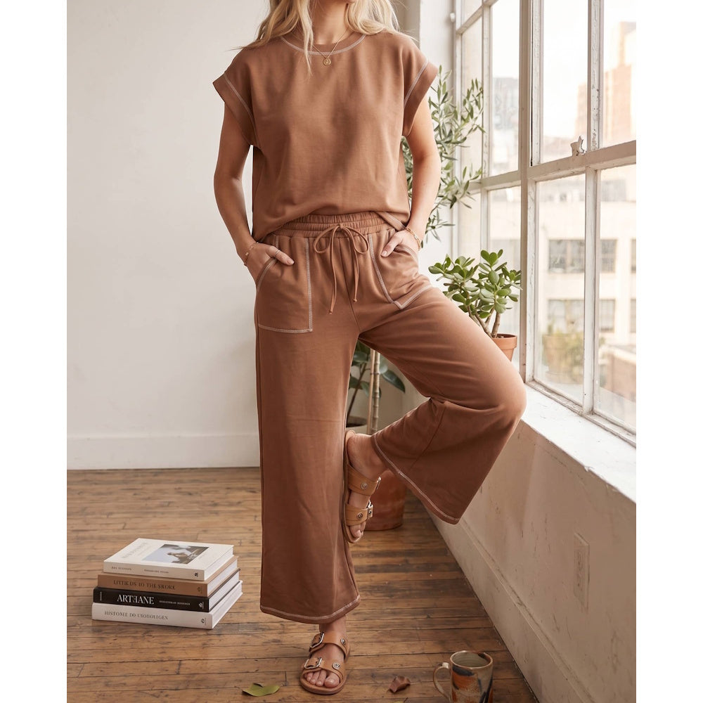 Woman wearing a brown lounge set with white contrast stitching, a short-sleeve tee, and wide-leg pants.