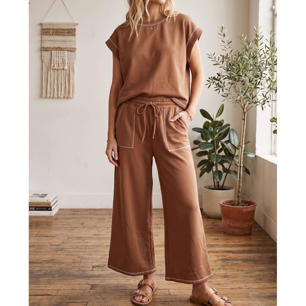 Woman wearing a brown short-sleeve top and wide-leg lounge pants set with white contrast stitching.