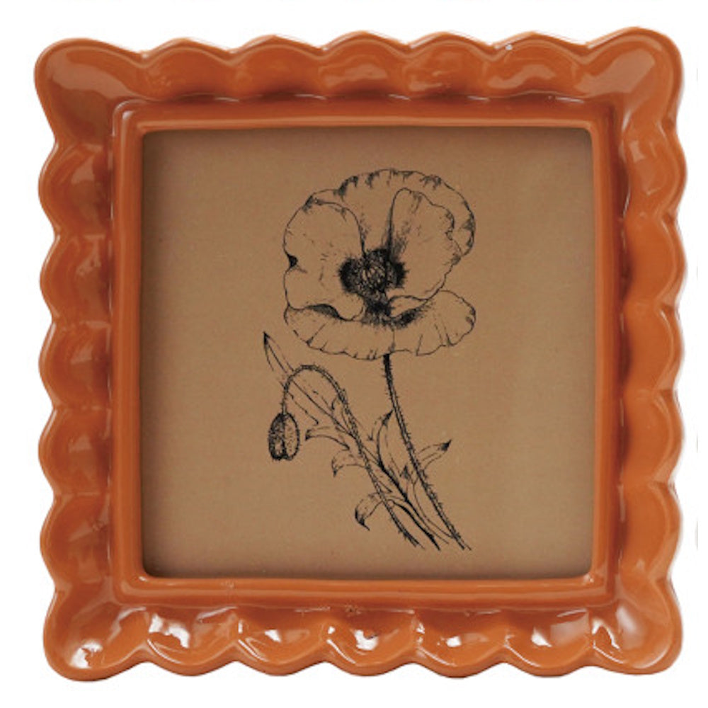 Square orange-brown ruffled picture frame featuring a black ink sketch of a poppy flower.