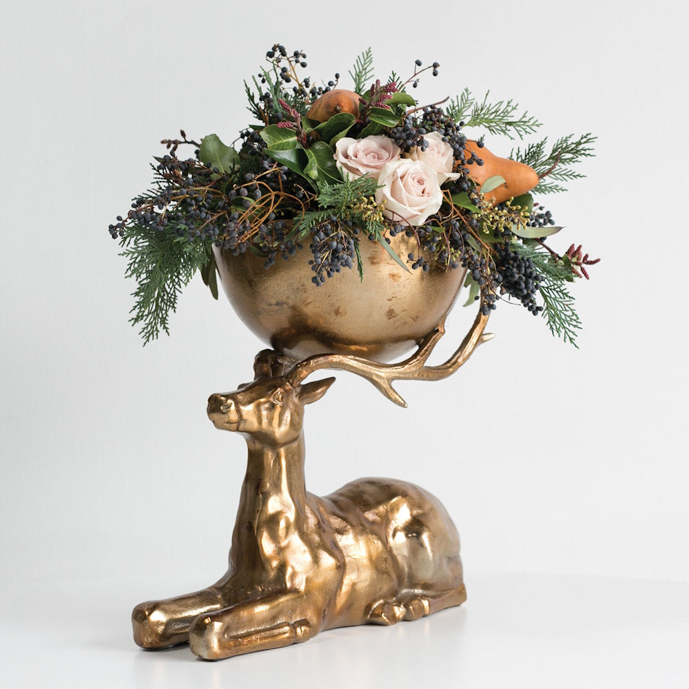 Antique gold stag bowl centerpiece filled with roses, greenery, berries, and pears.