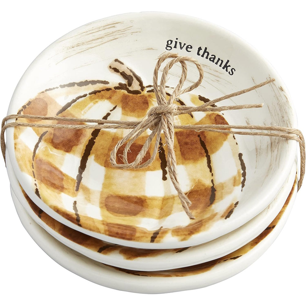 Stacked ceramic small plates featuring a plaid pumpkin design, "give thanks" text, and tied with twine.