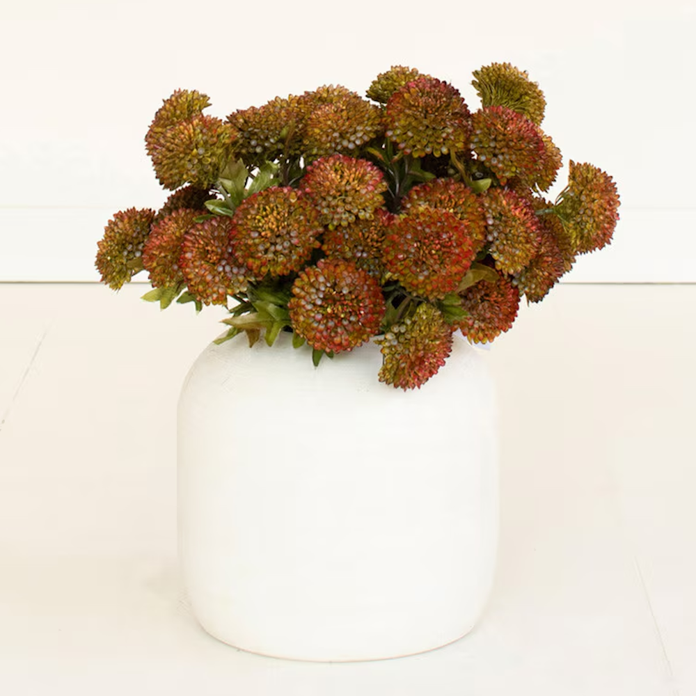 Lush arrangement of artificial auburn ball dahlias presented in a matte white ceramic vase.