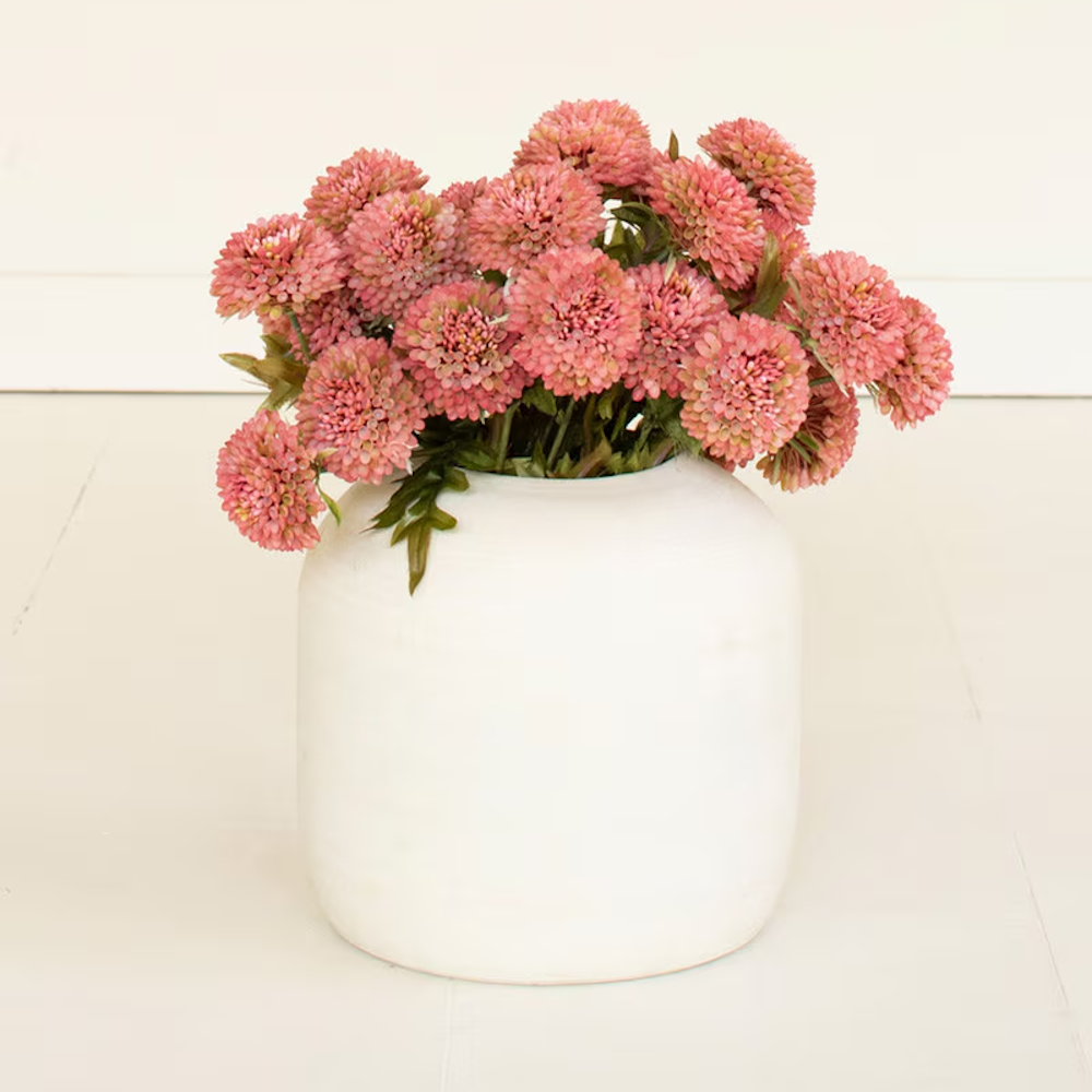 Artificial blush pink ball dahlia flower bundle in a white ceramic vase.