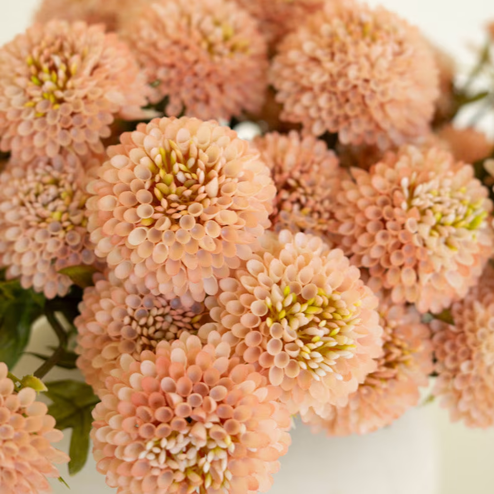 A bundle of light peach artificial ball dahlia flowers in a close-up shot, highlighting detailed round petals.