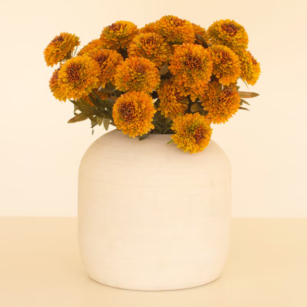 Lush arrangement of artificial mustard yellow ball dahlias displayed in a matte white ceramic vase.