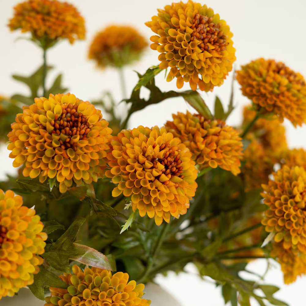 Close-up view of artificial mustard yellow ball dahlias highlighting textured petal layers.