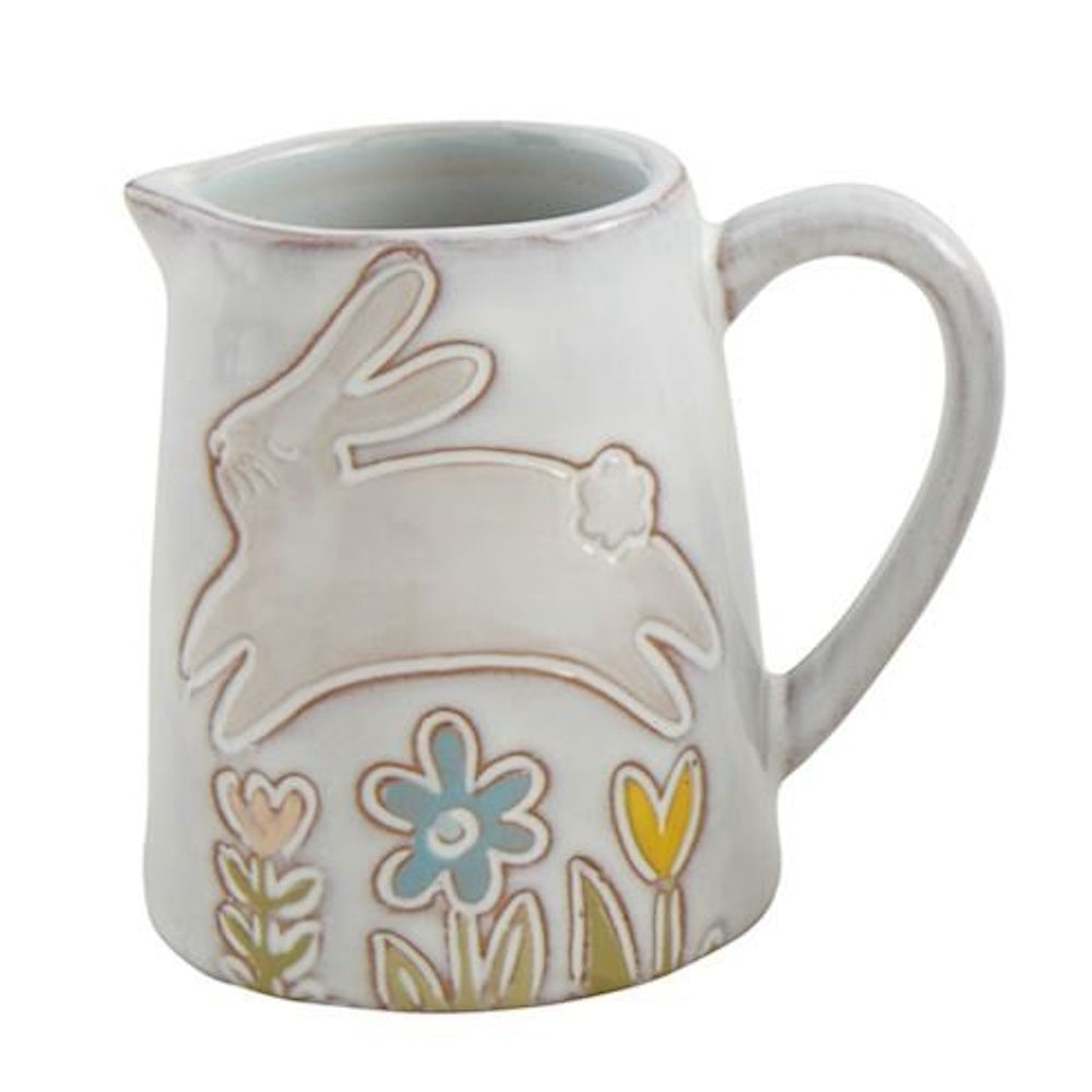 White ceramic pitcher featuring a raised design of a leaping bunny and colorful flowers.