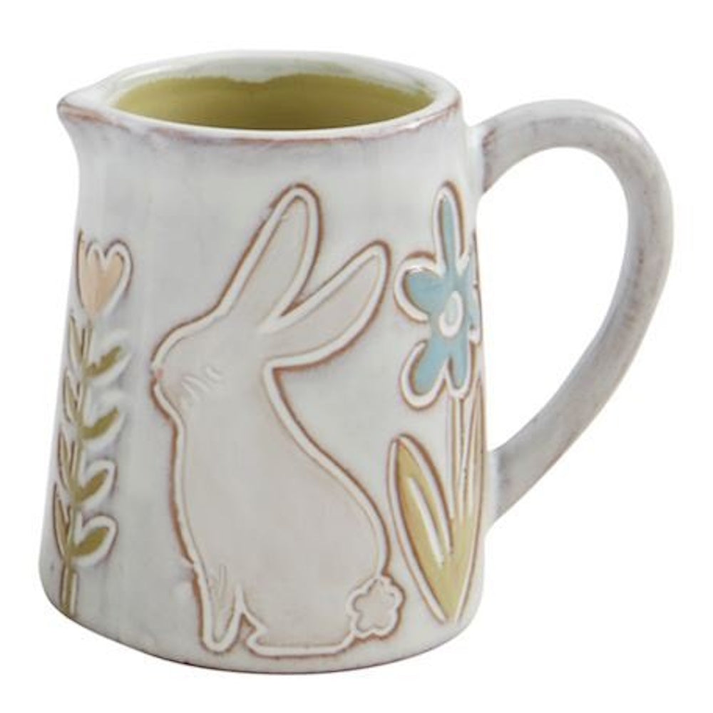 White ceramic pitcher decorated with an embossed rabbit and pastel flowers.
