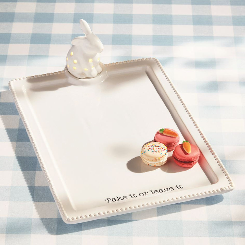 White ceramic bunny light-up serving tray with macarons and "Take it or leave it" text on a blue gingham tablecloth.