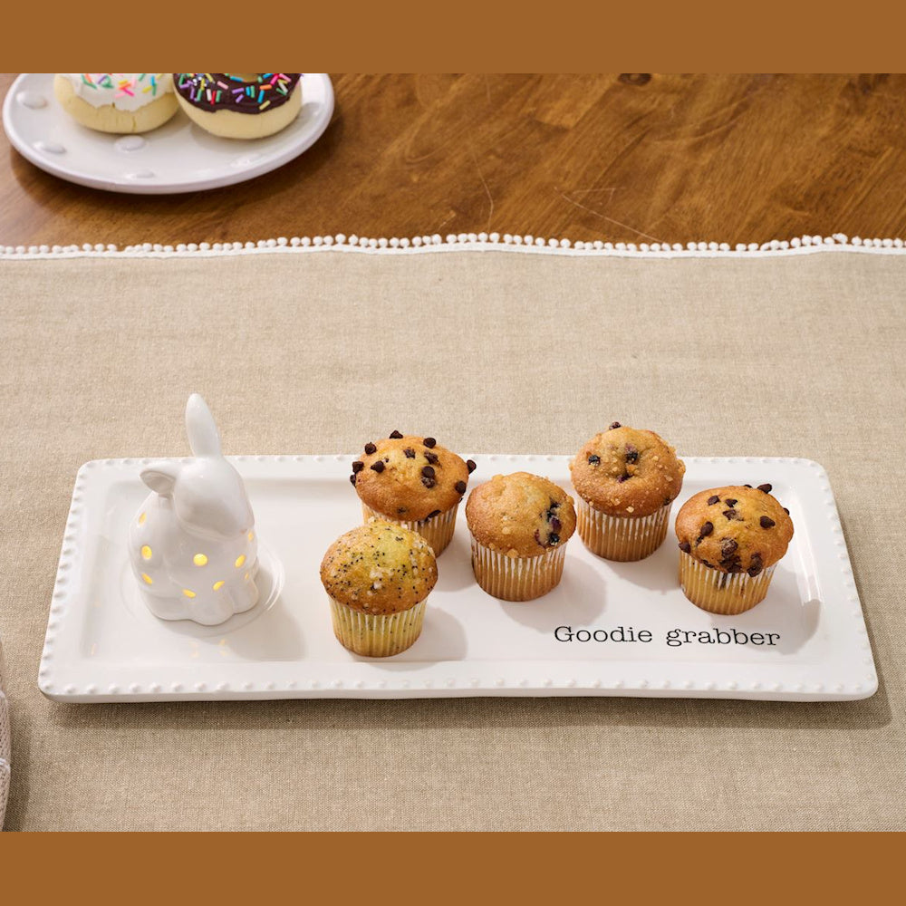 White ceramic bunny light-up sitter on a "Goodie Grabber" tray with assorted muffins and donuts on a table.