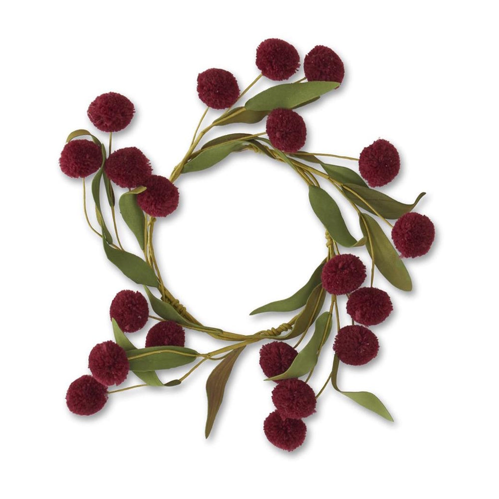 A circular wreath made of green leaves and fluffy burgundy pom-pom berries on a white background.