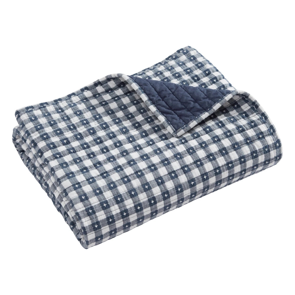 Folded navy and white gingham quilted throw blanket with a solid navy blue reverse side.