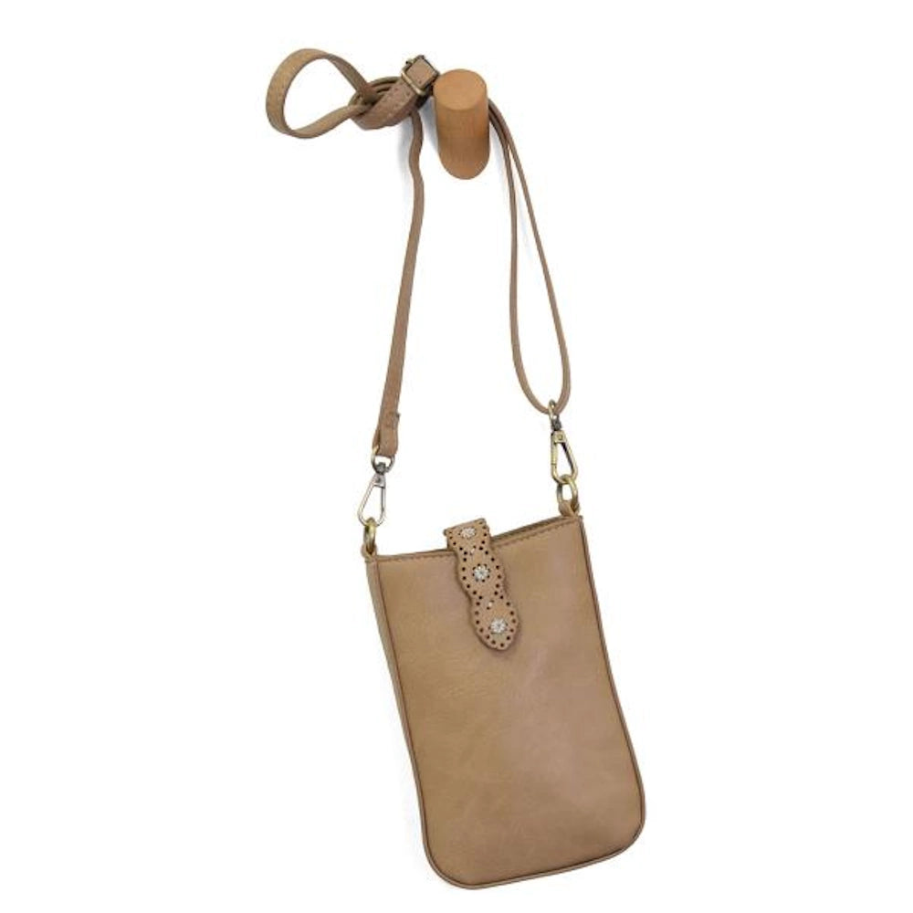 Camel crossbody phone bag with laser-cut daisy patterns on the strap and gold-tone hardware hanging on a wooden peg.