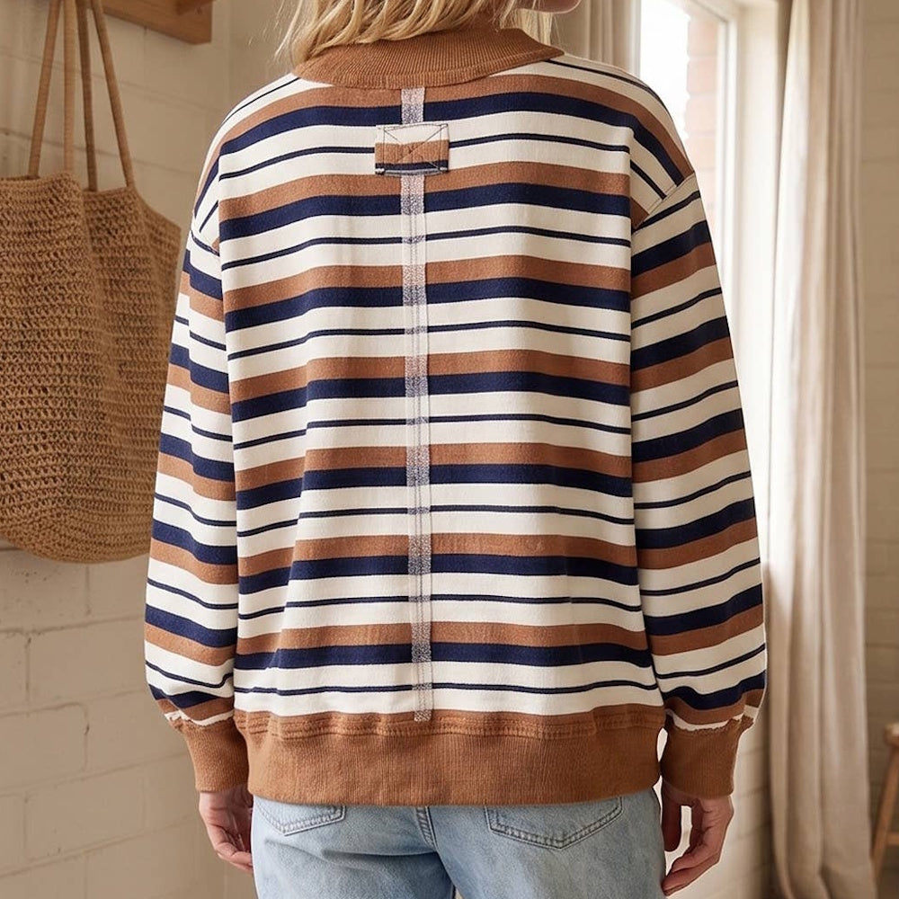 Back view of a woman wearing an oversized sweatshirt with camel brown, navy blue, and cream horizontal stripes.