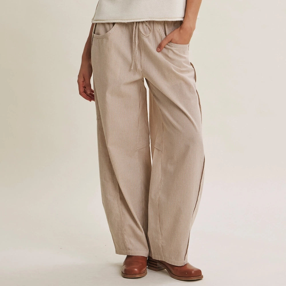 Relaxed beige fine-striped barrel-leg pants featuring a drawstring waist and curved seam details.