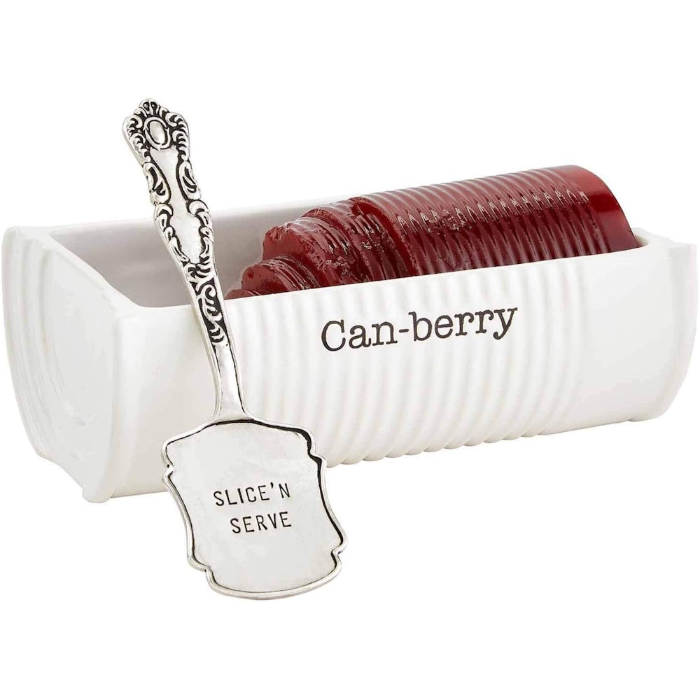 White ceramic cranberry dish labeled "Can-berry" with sliced sauce and a silver server.