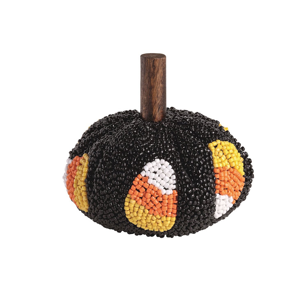 Decorative black beaded pumpkin with candy corn details and a wooden stem on a white background.
