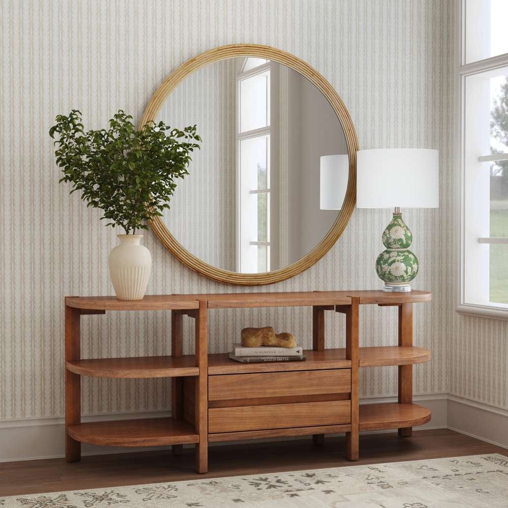 Modern wooden sideboard with round rattan mirror, floral lamp, and greenery in a stylish living room.